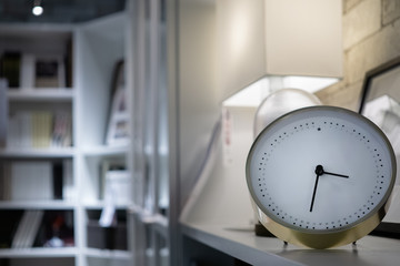 Modern white clock in the living room with book shelves and lamp