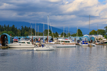 Fototapeta na wymiar Boats docked at Coal Harbor in Vancouver Canada with Stanley Park and Grouse Mountain in the background