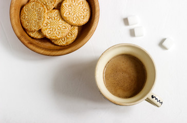 Coffee with milk in an old cup, served with biscuits and sugar on a light background.