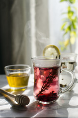 Refreshing herbal tea with honey is on the table by the window