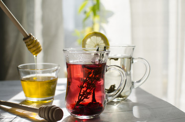 Refreshing herbal tea with honey is on the table by the window