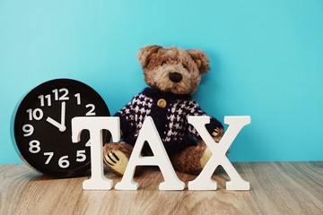 teddy bear and tax alphabet letters on wooden background