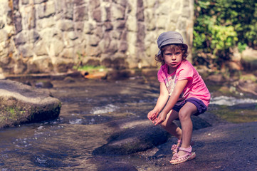 The little girl is playing in a mountain stream