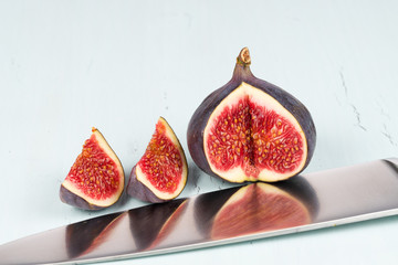 A whole with a cutout and small piece of ripe, delicious and sweets figs with a kitchen knife on a...