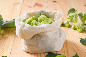 Fresh cones of hops in bag on  wooden background, Ingredient in beer industry. Craft beer brewing. For ale or lager