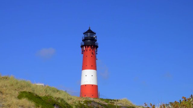 Wundersch&ouml;ner Leuchtturm H&ouml;rnum Sylt mit D&uuml;nen Landschaft  und blauen Himmel
