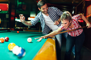 Young couple playing snooker together in bar