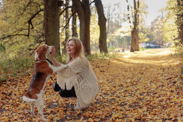 Young beautiful girl playing with a dog in the park.