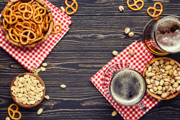 Light and dark german beer in big mugs and bowls with salty snacks and nuts, autumn beer festival concept, dark wooden table, top view