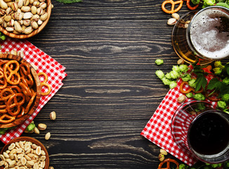 Light and dark german beer in big mugs and bowls with salty snacks and nuts, autumn beer festival concept, dark wooden table, top view