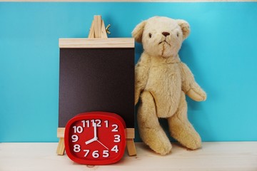 teddy bear and alarm clock with space copy on wooden background