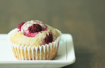 Fresh Home made bakery. Raspberry muffin on white plate with dark wood background. Delicious as restaurant quality