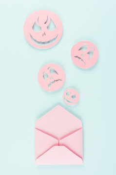 Halloween mock up with open envelope and spooky faces emoji as message of cut paper on pastel trendy mint background.