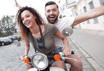 Couple riding motor scooter in old city street. © ASDF