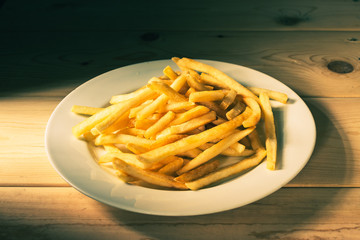 pile of french fries on white plate and wooden plank