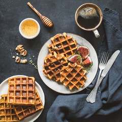Belgian waffles with figs and honey for breakfast on black background. Top view. Square crop. Tasty breakfast with waffles, coffee and honey