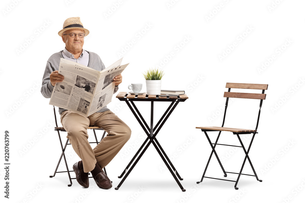 Poster senior sitting at a coffee table and holding a newspaper