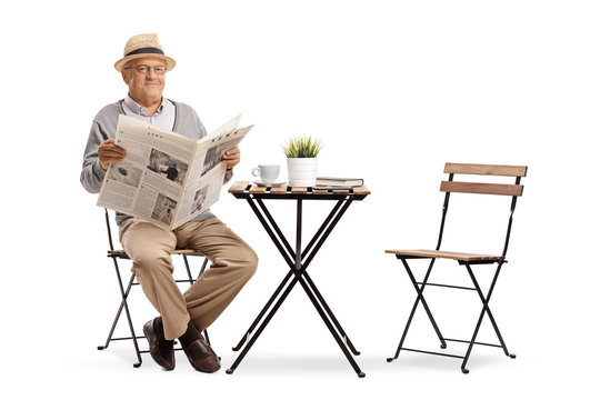 Senior sitting at a coffee table and holding a newspaper
