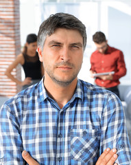 Casual businessman with arms crossed standing in the office