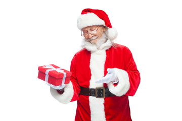 Christmas. Smiling Santa Claus in white gloves is holding a gift red box with a bow. Pointing at the gift. Isolated on white background.