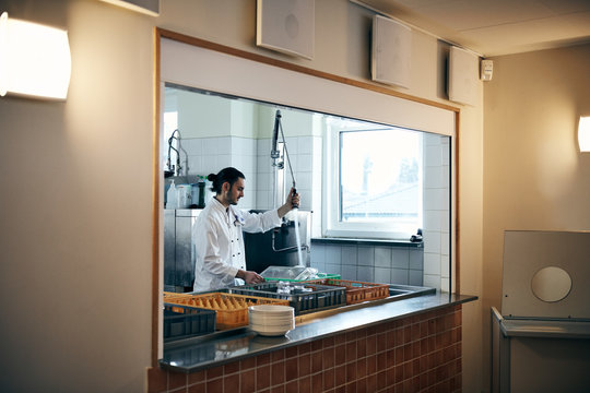 Male chef washing dishes seen through kitchen window