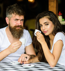 Couple in love drink black espresso coffee in cafe. Man with beard and attractive happy smiling girl hold hands drinking coffee. Couple happy spend time in cafe. Enjoy moment with cup of coffee drink