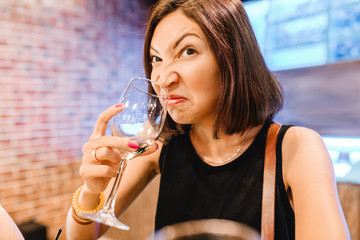 A woman at the tasting tries and smells the aroma of an ugly glass of wine. Concept of alcoholism...