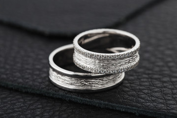 Obraz na płótnie Canvas Two silver wedding rings on black leather background