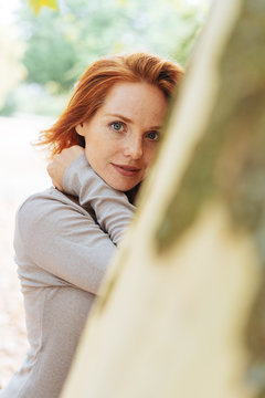 Young redhead woman smiling quietly at the camera