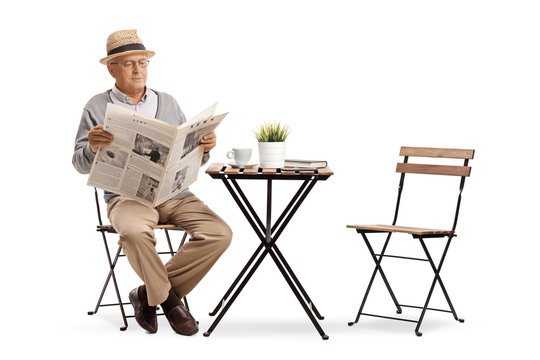 Senior sitting at a coffee table reading a newspaper