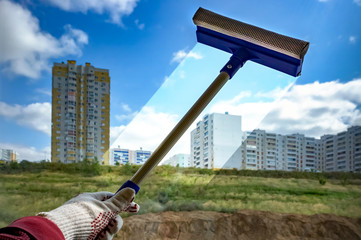 Washing the window. The brush cleans the window glass through which the city houses are visible.