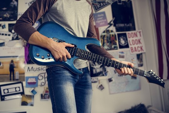 Teenage boy playing an electric guitar in a bedroom hobby and music concept