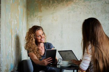 Two women sitting in cafe and using laptop for shopping on line.