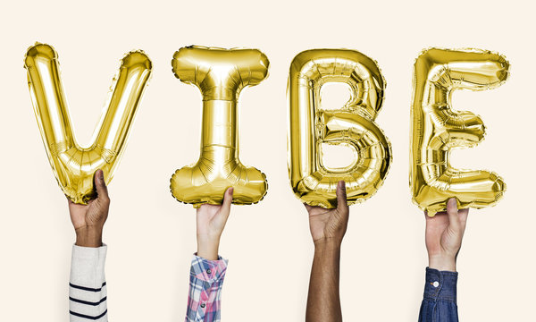 Yellow gold alphabet balloons forming the word vibe