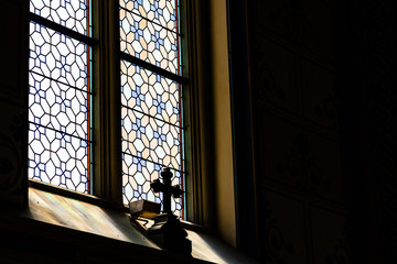 Mystic cross in the shadow in front of the stained transparent glass in a  gothic catholic cathedral