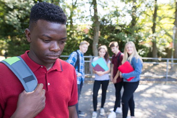 Unhappy Teenage Boy Being Gossiped About By School Friends