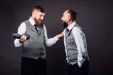 Two bearded men in suits talking and gesticulating to each other on black