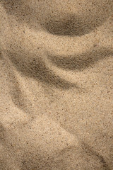 Sunny sand texture, small bizarre dunes on the beach, background with copy space