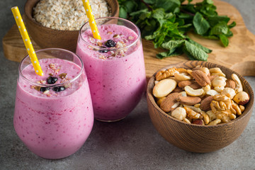 Glasses of berry smoothie with nuts, mint, blueberry, blackberry, raspberry, and yogurt on wooden table. Weight loss and diet concept. 