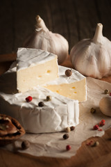 Camembert and brie cheese on wooden background with tomatoes, letuce and garlic. Italian food. Dairy products.