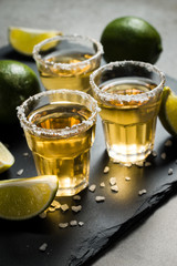 Macro photo of shots of gold Mexican tequila with lime and salt on wooden rustic background. Alcoholic drink concept. selective focus.