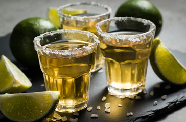 Macro photo of shots of gold Mexican tequila with lime and salt on wooden rustic background. Alcoholic drink concept. selective focus.