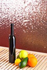 Bottle of wine and fruits on wooden surface, shimmering background. Fruits as orange, apple and...