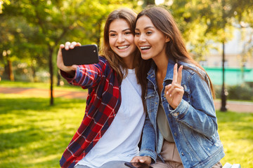 Women friends students walking in the park make selfie by mobile phone.