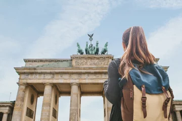 Fotobehang Een toeristisch meisje met een rugzak of student die naar de Brandenburger Tor in Berlijn in Duitsland kijkt. © franz12