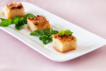 Three piecies Basbousa or Namoora traditional arabic dessert. Delicious homemade semolina cake with nuts on white plate. Copy spase. Selective focus.