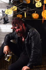 Halloween party concept. Man wearing scary makeup holds beer mug