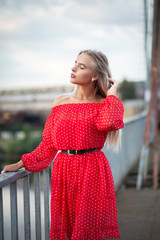 Glamor blonde girl with closed eyes posing on the bridge in the evening