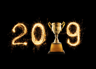 2019 written with Sparkle firework with champion golden trophy on black background.