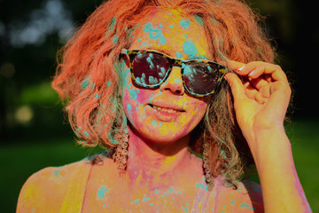 Adorable caucasian model wearing glasses covered by dry Holi paint